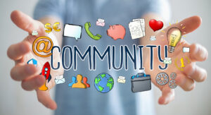 Businessman using hand-drawn community presentation The word community surrounded by different icons in front of someone holding out their hands.