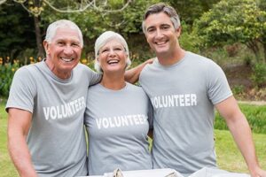 Three people with arms around each other, smiling and wearing shirts that say Volunteer