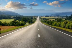 Two lane road going off into the distance with mountains in the background