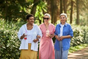 Three older women walking outside with arms linked